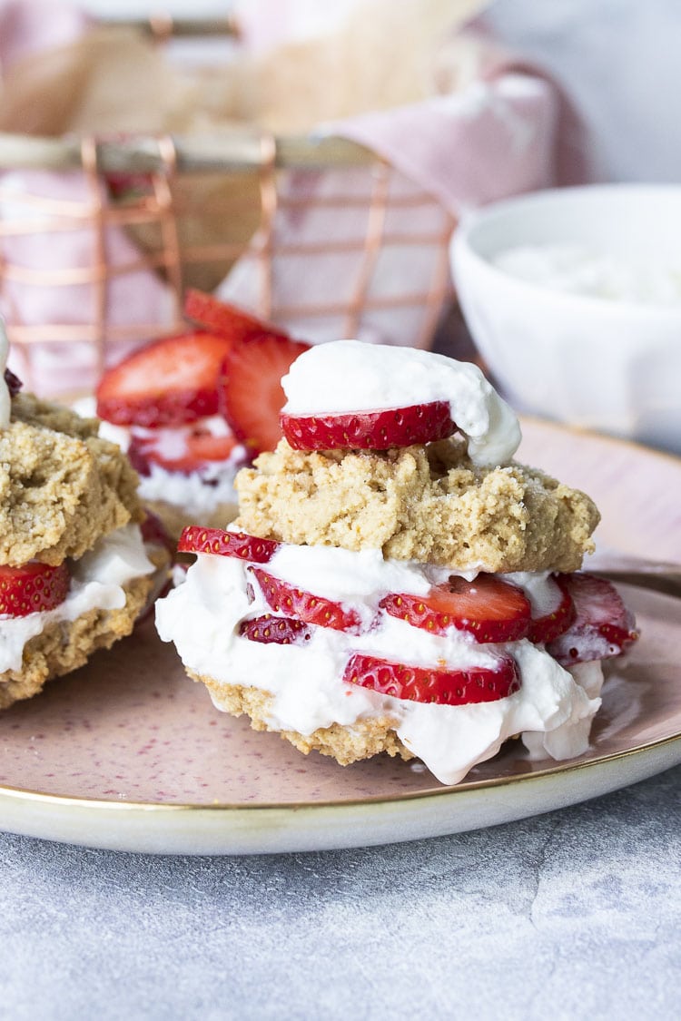 Front view of vegan strawberry shortcake layered with strawberries and whipped cream in between two biscuits