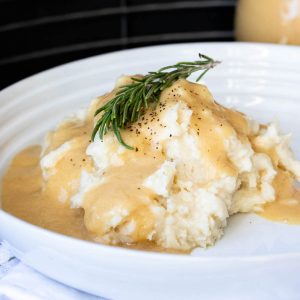 Rosemary sprig on a pile of mashed potatoes covered in gravy