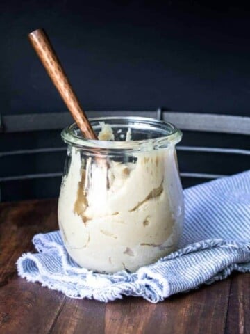 Copper spoon in a glass jar of cashew cream cheese.