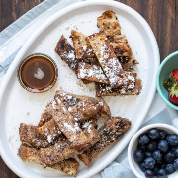 White platter with french toast sticks and bowls of toppings