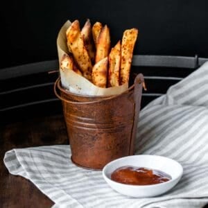 A brown pail with parchment in a cone filled with fries.