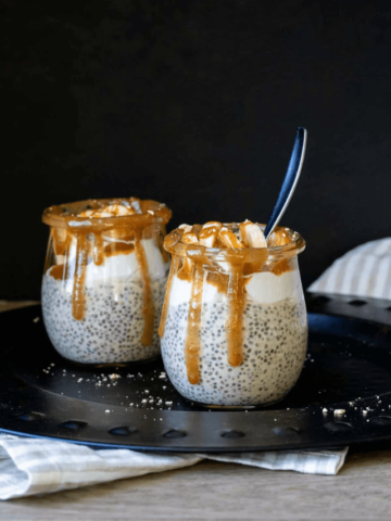 Two glass jars with chia pudding in them topped with a dripping caramel around the edges.